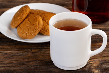 White porcelain cup of tea and oat cookies on a table