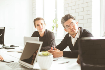 A team of young businessmen working and communicating together in an office. Corporate businessteam and manager in a meeting.