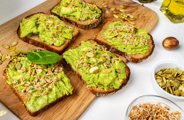 Sandwiches with avocado guacamole on a wooden board on the table. Healthy food concept.