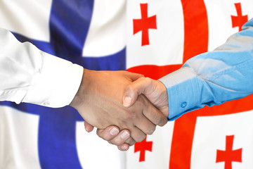 Handshake on Finland and Georgia flag background.
