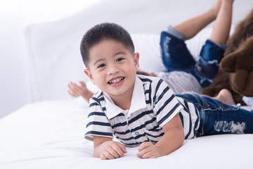 Selective focus Asian adorable boy kid happy playing on bed at home, Asian preschool cute boy kid playing on bed with hiding in white pillows, happy lifestyle boy kid on bed with copy space