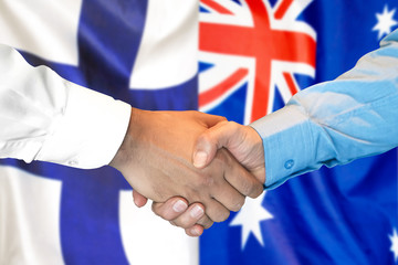 Handshake on Finland and Australia flag background.