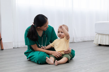 Asian pediatrician doctor woman green uniform hold stethoscope annual check up toddler boy by...