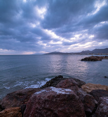 Scenic landscape of the sea with mountains on the background and rocks on the foreground