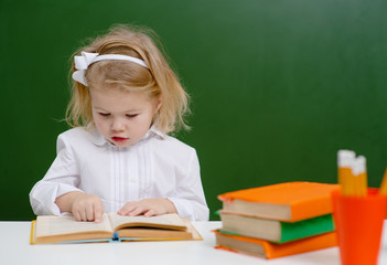 Little girl reading a book in school