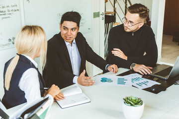 A team of young businessmen working and communicating together in an office. Corporate businessteam and manager in a meeting.