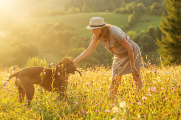 Woman with a dog playing on a mountain