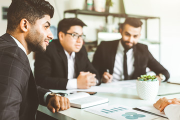 A team of young businessmen working and communicating together in an office. Corporate businessteam and manager in a meeting.