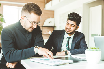 A team of young businessmen working and communicating together in an office. Corporate businessteam and manager in a meeting.
