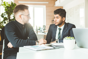 A team of young businessmen working and communicating together in an office. Corporate businessteam and manager in a meeting.