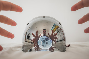 Homem pegando a lua ao espelho do capacete no quarto branco