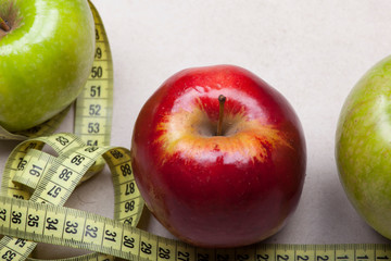 green and red big apple photographed with a tailor on a light background