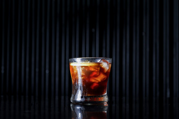 glass of whiskey with ice on black background