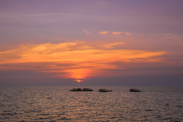 Group of boats on a wide sea during beautiful pink sunset in Thailand Asia