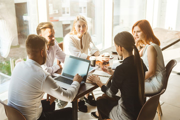 A team of young businessmen working and communicating together in an office. Corporate businessteam and manager in a meeting.