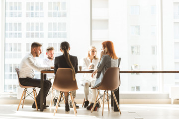 A team of young businessmen working and communicating together in an office. Corporate businessteam and manager in a meeting. desktop against the background of the pan window, free space for text