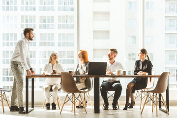 A team of young businessmen working and communicating together in an office. Corporate businessteam and manager in a meeting. desktop against the background of the pan window, free space for text