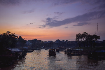 Tourist boats driving through floating native floating village on pylons Kampong Phluk in Cambodia Asia