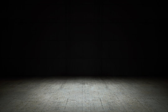 Dark empty room with black background and dim light on concrete floor