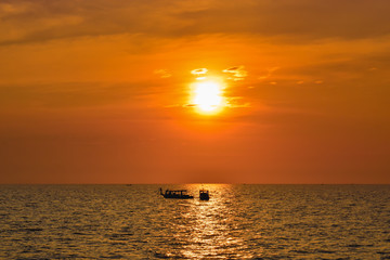 Naklejka na ściany i meble Two lonely ships on a wide ocean during beautiful orange sunset in Asia