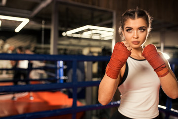 Obraz na płótnie Canvas fit slim caucasian woman training, boxing in ring, wearing red protective bandages and sportive wear. sport, box, fitness concept