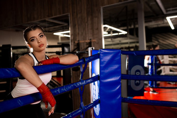 exhausted woman stand near fence of ring, after active training, fighting with opponent in sportive wear . Sport as hobby, box concept