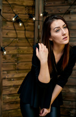 The concept of a glamorous portrait. Portrait of a pretty brunette girl in a black fashion suit on a stylish background in the original interior. Stands in front of the camera in various poses.