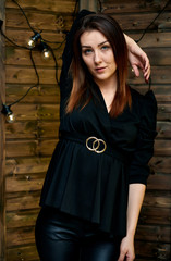 The concept of a glamorous portrait. Portrait of a pretty brunette girl in a black fashion suit on a stylish background in the original interior. Stands in front of the camera in various poses.
