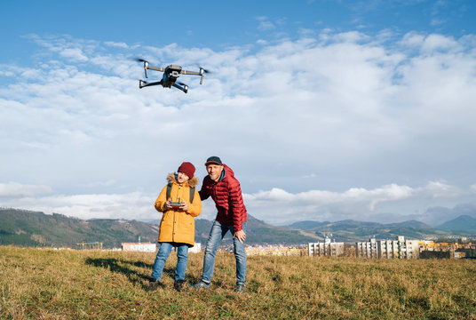 Father and Teenager boy son dressed yellow jacket piloting a modern digital drone using remote controller. Modern technology devises concept image