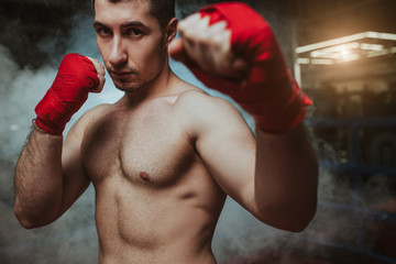 portrait of confident, brutal muscular boxer man with naked skin isolated over smoky space, ring or gym. Sport, box, training, exercising concept