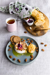  baked cheese with nuts, honey and jam on a ceramic plate, complemented by slices of bread baguette