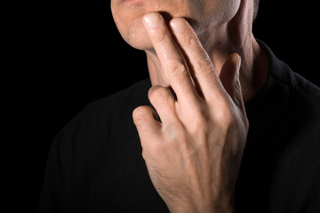 The man shaved his beard and touched his face. Close-up, black background.