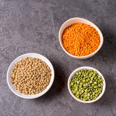 Top view of assortment of peas, lentils, beans and legumes over gray background.