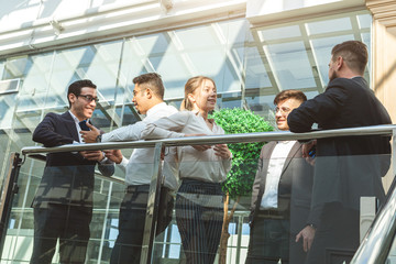 young business people are standing and talking on the background of glass offices. Corporate businessteam and manager in a meeting.