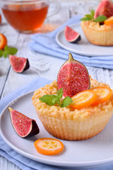 Grated mini pie with cottage cheese topped with pieces of figs and kumquats on ceramic plate