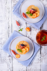 Grated mini pie with cottage cheese topped with pieces of figs and kumquats on ceramic plate