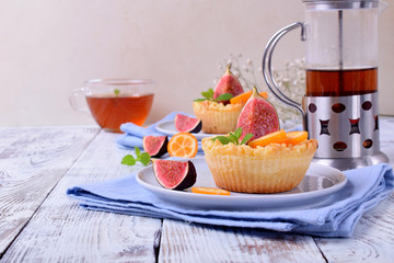 Grated mini pie with cottage cheese topped with pieces of figs and kumquats on ceramic plate