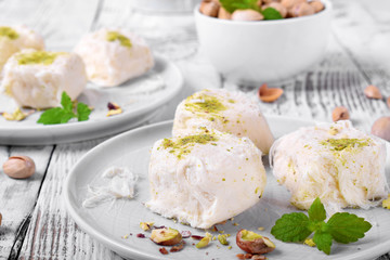 Cotton candy with pistachio on ceramic plate on white wooden table