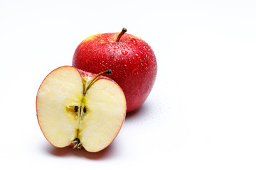 Ein halber Apfel durchgeschnitten mit Kernen und Stil im Hintergrund ein weterer Apfel mit Wasser Perlen, hinterer Apfel im Fokus