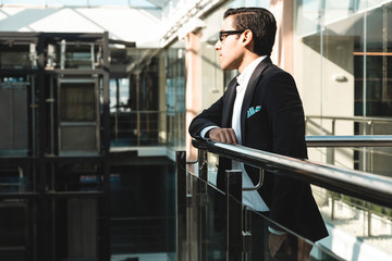 Portrait of a businessman in suit are standing on the background of glass offices.