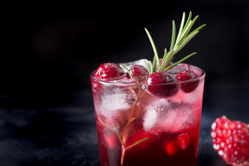 Pomegranate Christmas cocktail with rosemary, sparkling wine, club soda on black. Close up.