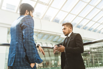 young business people are standing and talking on the background of glass offices. Corporate businessteam and manager in a meeting.
