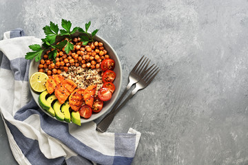 A bowl of healthy vegan salad, fried chickpeas, fried sweet potatoes, avocado, quinoa, tomatoes and parsley. Top view, flat lay.