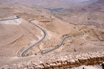 Rocky sandstone mountains landscape with a long road in Jordan