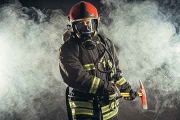 portrait of serious and confident caucasian fireman stand holding hammer, wearing special...