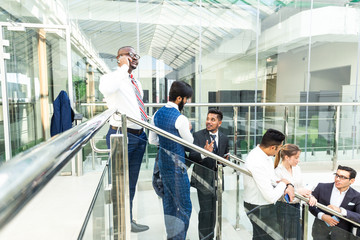 young business people arego down the stairs and talking on the background of glass offices. Corporate businessteam and manager in a meeting.