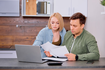 Finance managers task. young caucasian woman and man use laptop computer and document paper, sit on table and discuss