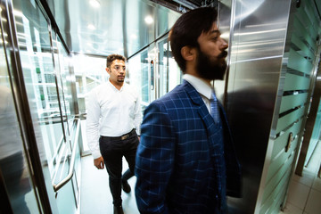 Business team group going on elevator. Business people in a large glass elevator in a modern office. Corporate businessteam and manager in a meeting.