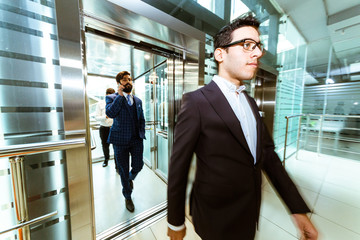 Fototapeta premium Business team group going on elevator. Business people in a large glass elevator in a modern office. Corporate businessteam and manager in a meeting.