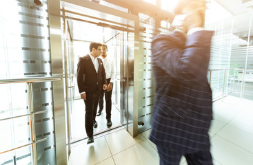Business team group going on elevator. Business people in a large glass elevator in a modern office. Corporate businessteam and manager in a meeting.